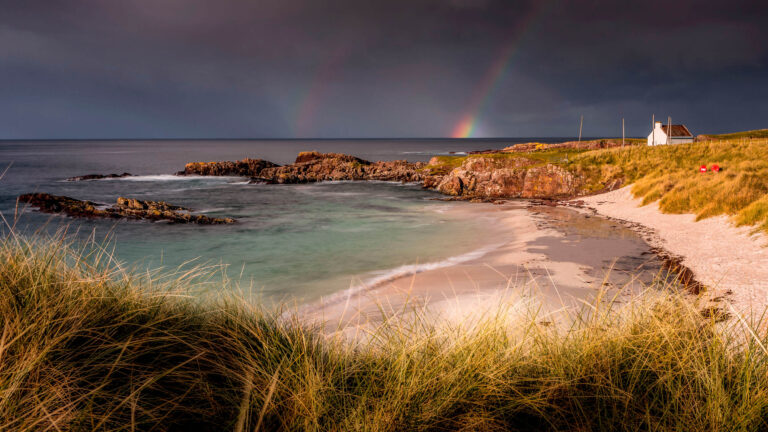 Photo of Clachtoll Beach and a rainbow after a storm, Scotland.