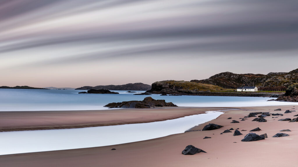 Serene beach with distant white house.