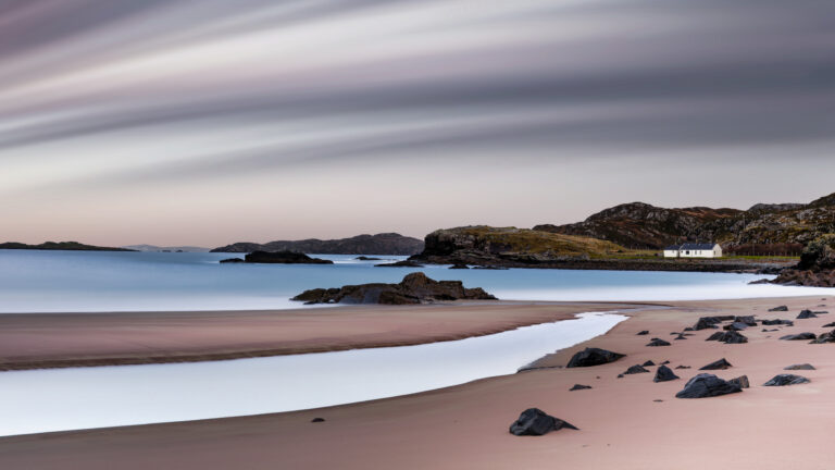 Serene beach with distant white house.